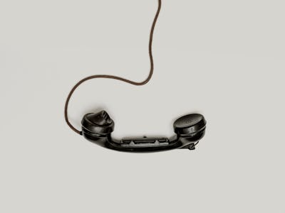 A black phone hanging from its cord