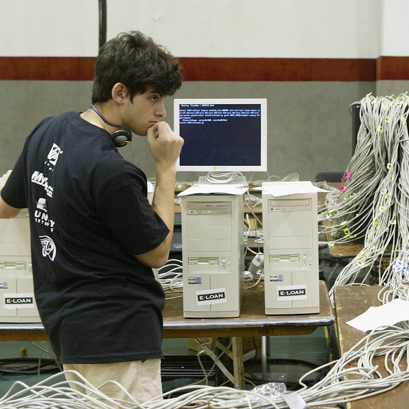 A boy standing next to a table with a computer