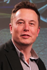 Elon Musk wearing a black suit and grey shirt