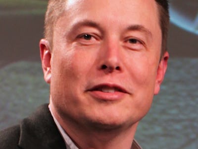 Elon Musk wearing a black suit and grey shirt