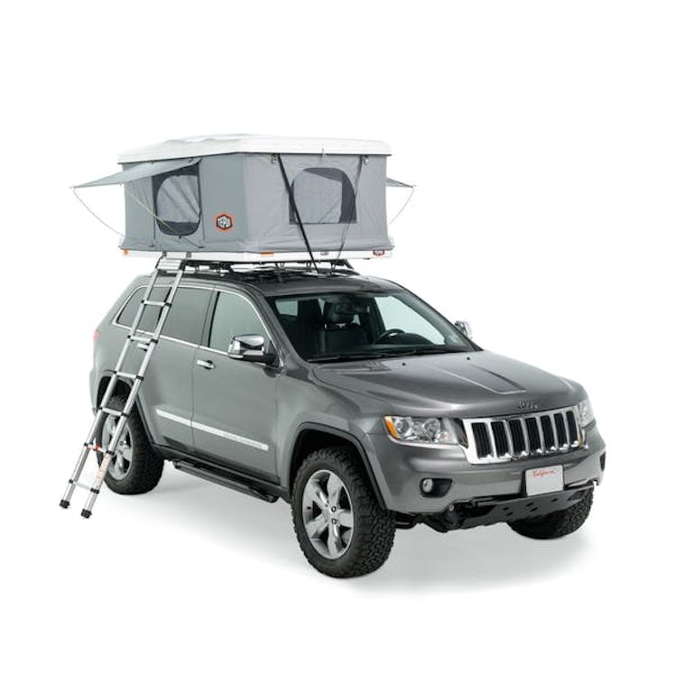 A silver Jeep with a canopy/storage unit on top.
