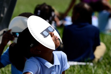 Kids looking at an eclipse with a plate and sunglasses on head