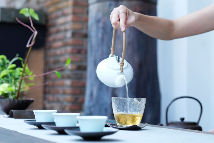 A hand pouring tea in a cup