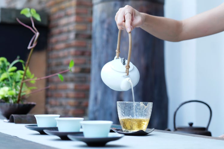 A hand pouring tea in a cup