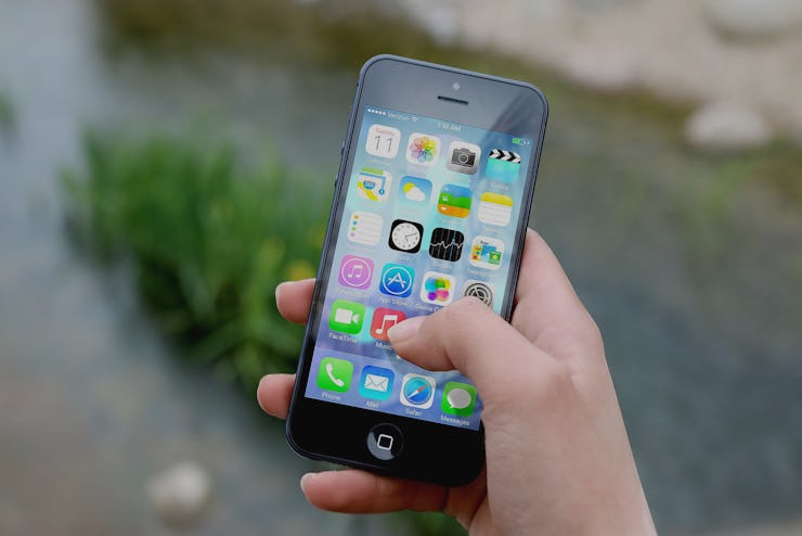 A person holding an iphone and scrolling through their apps while standing outside