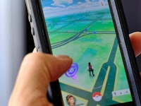 A hand holding a phone with 'Pokemon Go' game on the screen