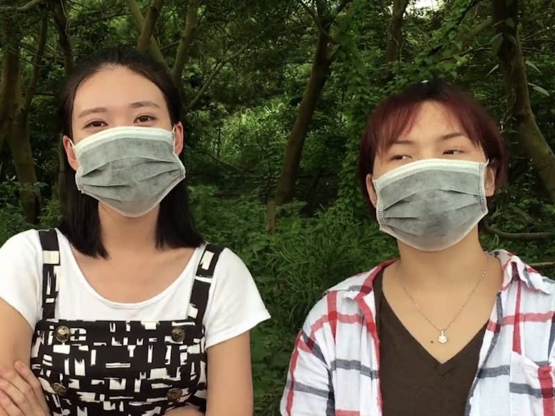 Two women standing with face masks over their mouths who know how to hack into a Tesla Model S.