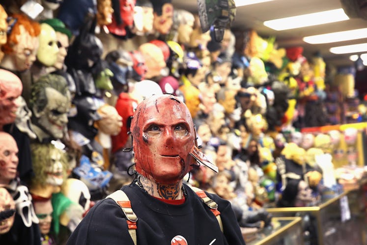 A man trying a red scary Halloween mask in a shop