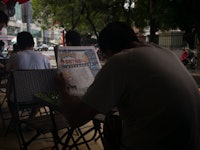 A man reading a newspaper article about "Pokémon Go"