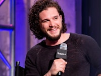 Kit Harrington standing with a microphone in his hand looking to the side
