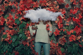 An art image of a woman lying in red flowers with a cloud covering her head
