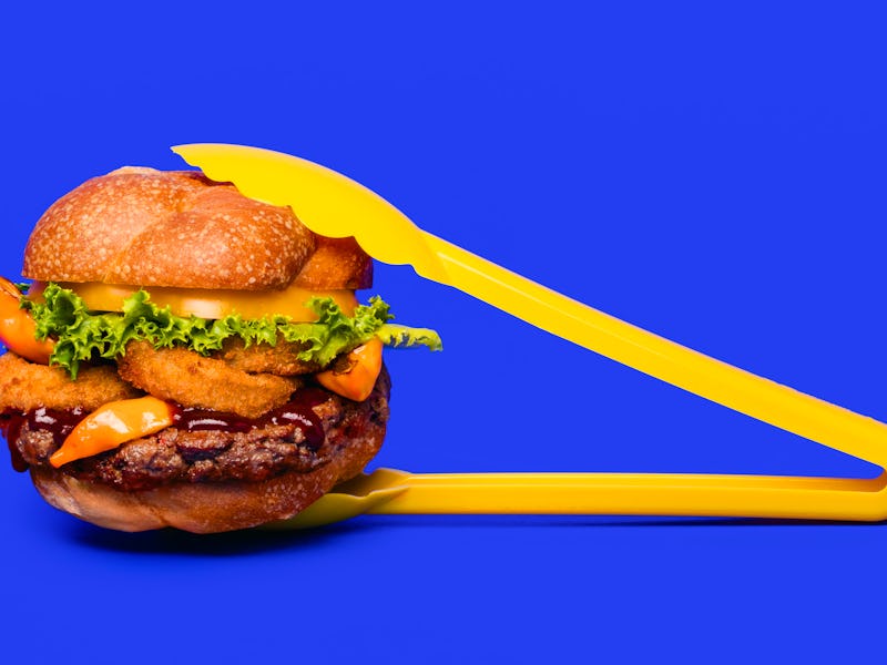 A freshly made Impossible Burger being held by yellow clamps