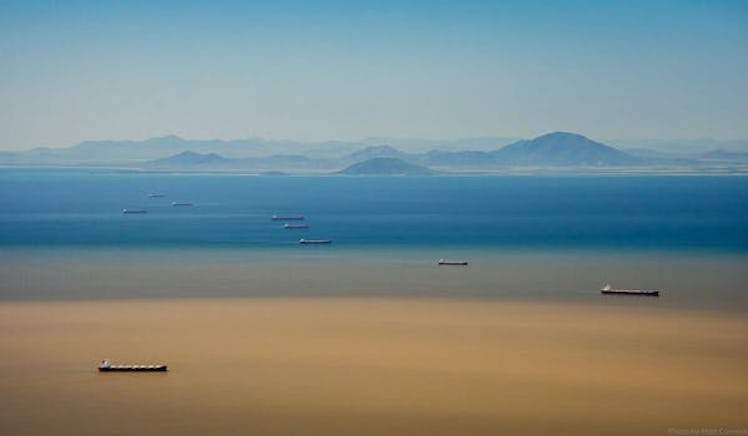 A photo depicting two threats to the Great Barrier Reef: coal ships anchored near Abbot Point and a ...