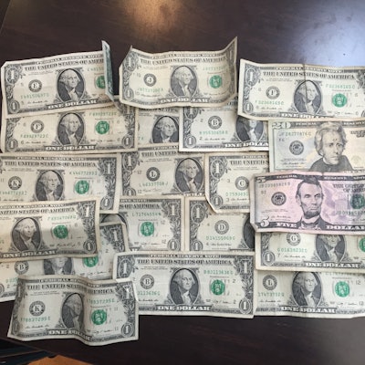 One dollar bills placed next to each other on a dark wooden surface