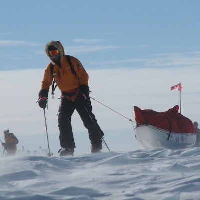 A motivated man exploring the South Pole on skis while dragging a ski bed