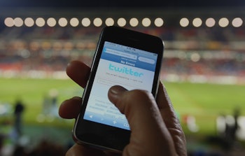 A man using his smartphone during a soccer game while a Twitter bug reveals the location of the user...