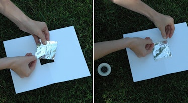 Hands taping foil over the hole in paper