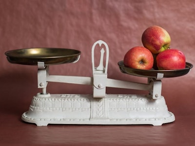 An old white scale with tree apples on one side, representing achieving work-life balance