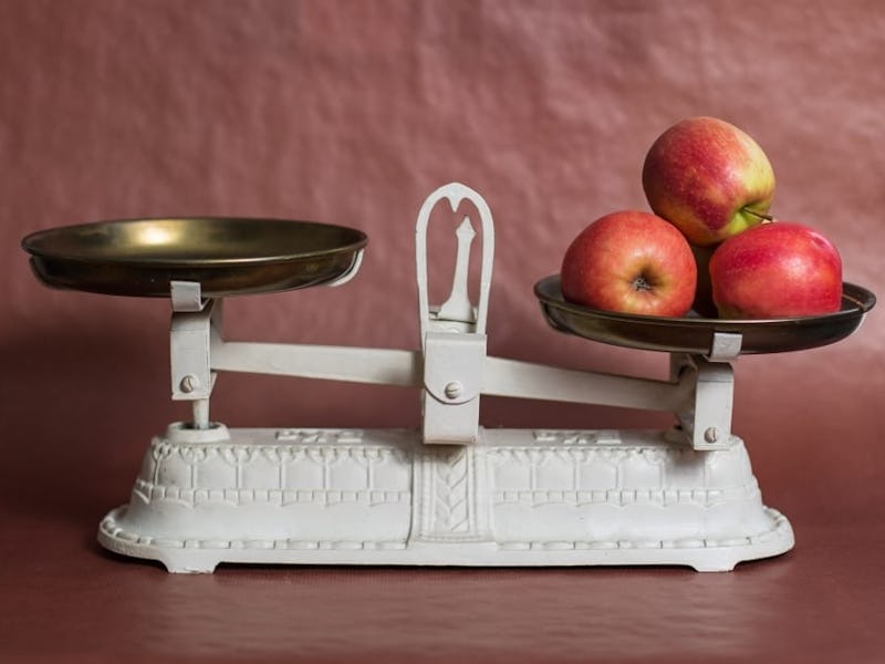 An old white scale with tree apples on one side, representing achieving work-life balance