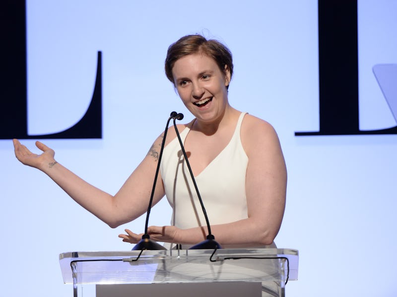 Lena Dunham in a white dress giving a speech at an event