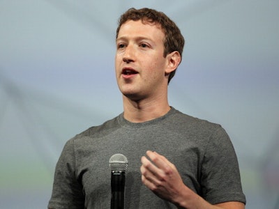Mark Zuckerberg giving a speech with a microphone in his hand, in a grey T-shirt.