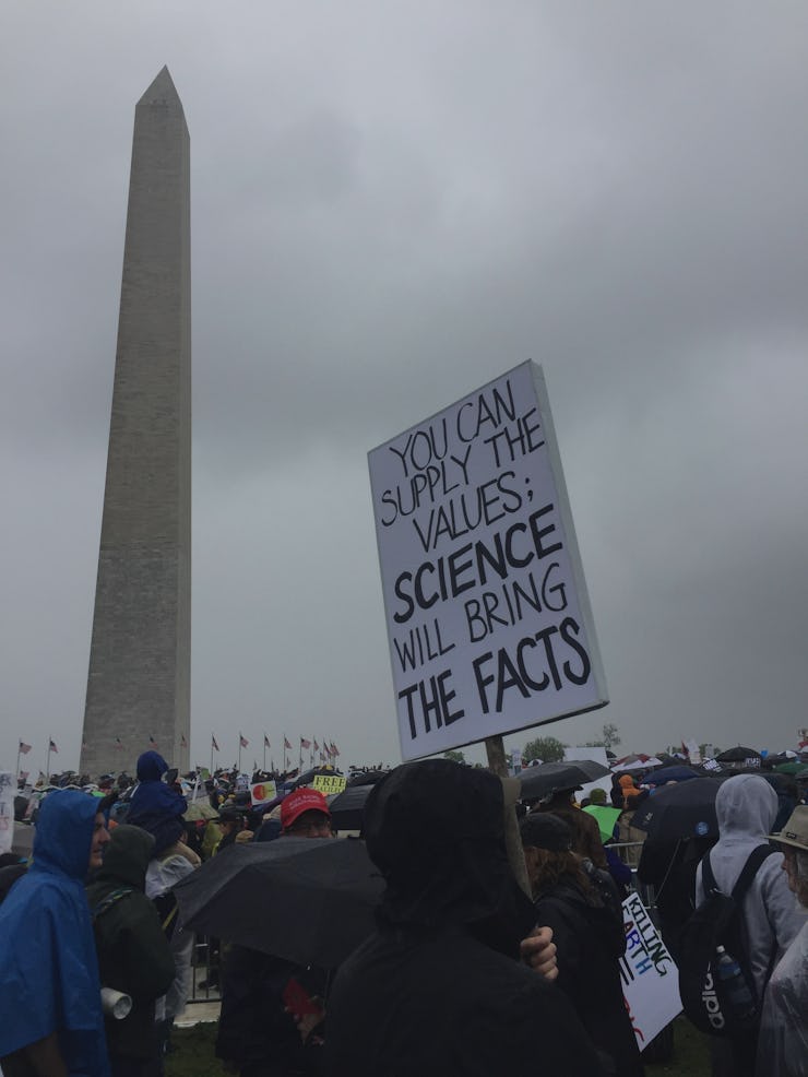 A group of people at the March for Science with a large poster and the Obelisk in the background in ...