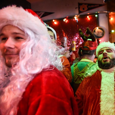 A group of men dressed as Santa Claus, drinking in a pub