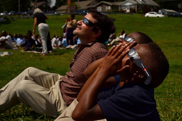 A group of Americans sitting at the grass, looking up and watching the eclipse