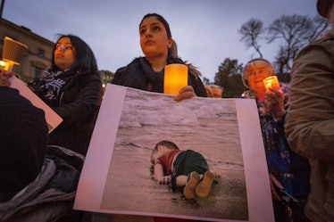 woman hold's photo of Aylan Kurdi at a vigil