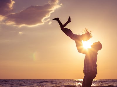 Father holding his son with his hands on the beach during sunset near the sea