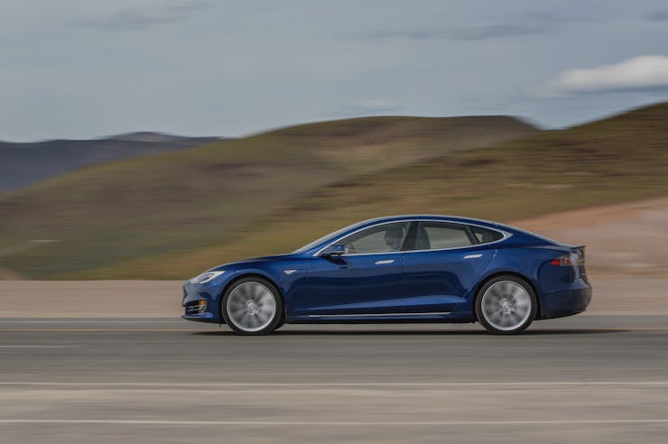 A blue tesla driving down a desert road at high speeds