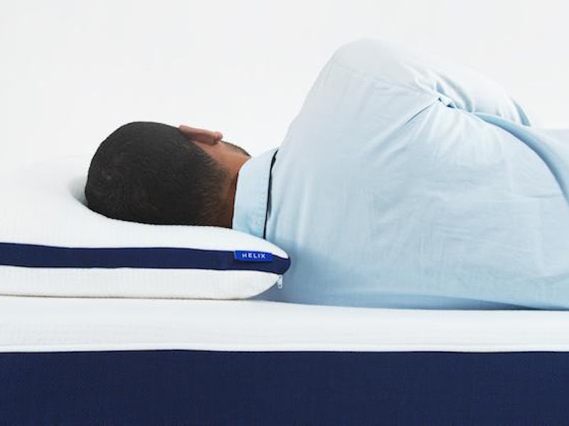 A man in a button up shirt lying on the perfect mattress for him after using a sleep quiz