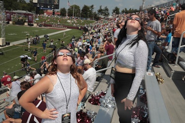 Two women at Saluki Stadium looking up and watching the eclipse