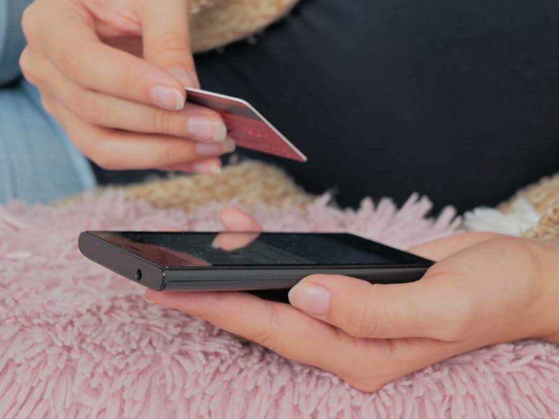 A closeup of a person holding their phone and credit card 