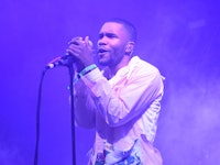 Frank Ocean performing live on stage bathed in a purple light