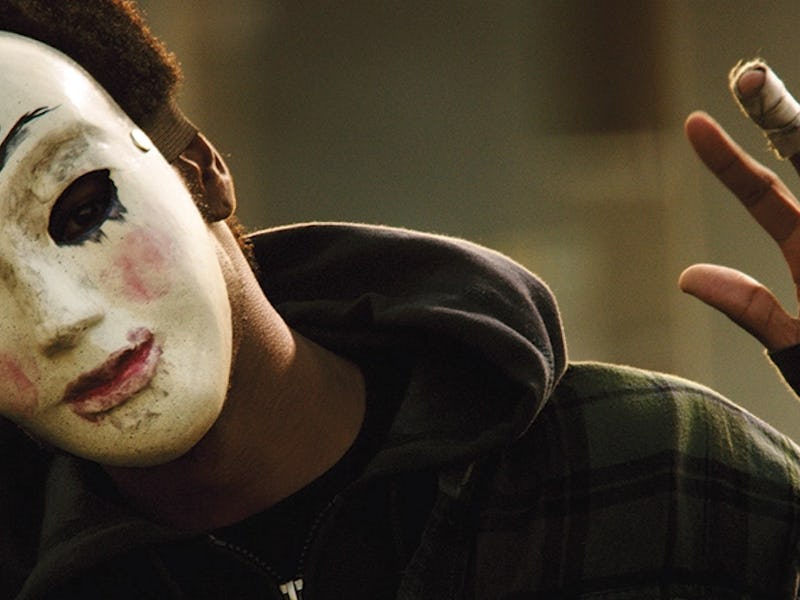 A man wearing a white mask with the God inscription on the forehead