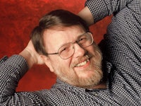 Ray Tomlinson, the Inventor of Email, posing in a black and white checked shirt and glasses