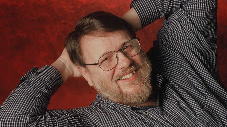 Ray Tomlinson, the Inventor of Email, posing in a black and white checked shirt and glasses