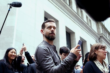 Twitter CEO Jack Dorsey standing outside with the phone in his hand where people are visible behind ...
