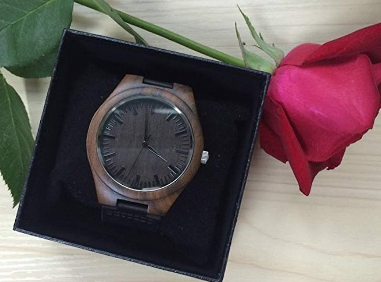 A customizable watch in a black box next to a rose