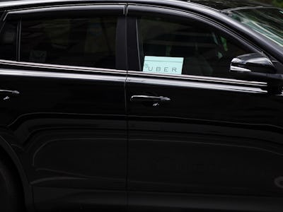 A black car with an Uber sign visible at the window