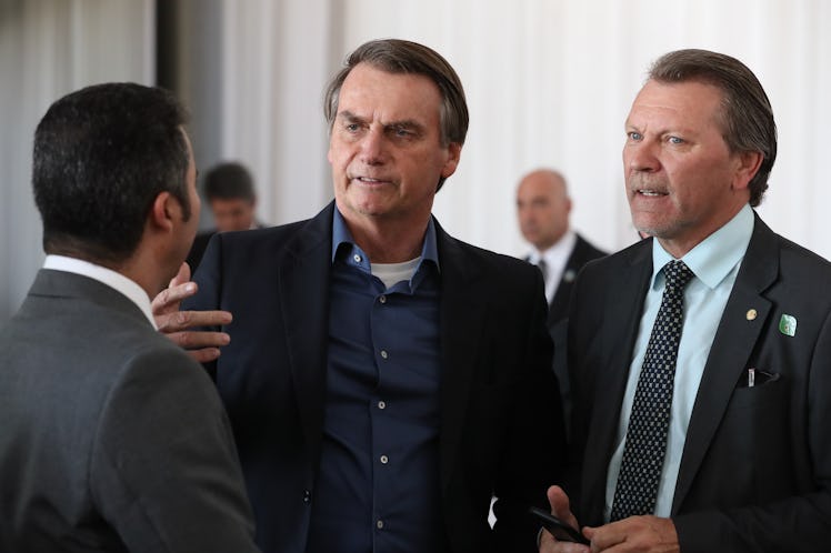 Brazilian President Jair Bolsonaro talks to two other men 