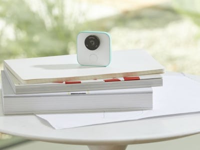 Google's New clips camera in white places on a pile of books on top of a white table outside