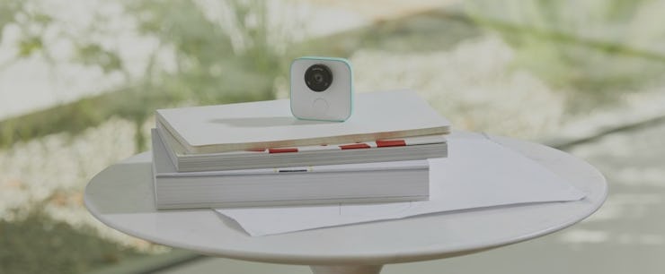 Google's New clips camera in white places on a pile of books on top of a white table outside