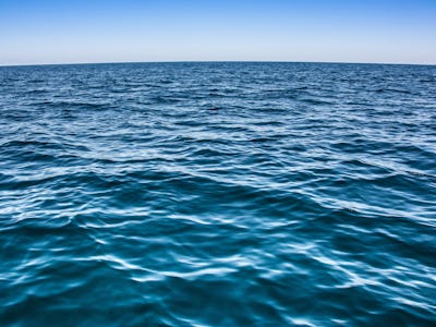 A blue surface level of an ocean and blue sky