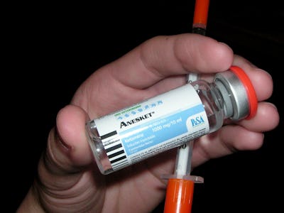 A hand holding a Ketamine bottle