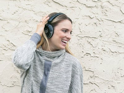 A woman wearing a grey sweatshirt using bluetooth headphones to listen to music