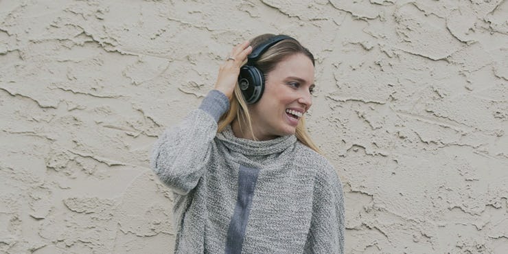 A woman wearing a grey sweatshirt using bluetooth headphones to listen to music