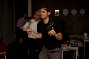 A man dancing while holding a glass of an alcohol drink