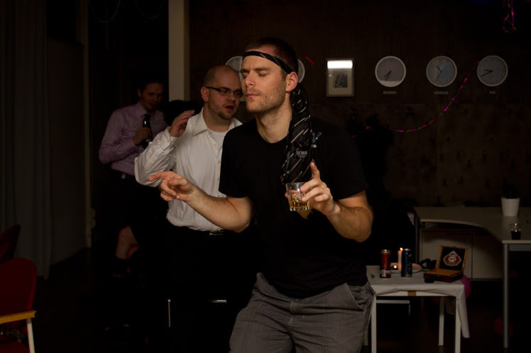 A man dancing while holding a glass of an alcohol drink